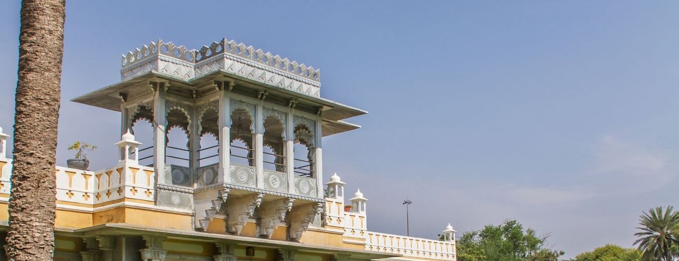 facade image of Dev Shree, deogarh featuring a vast levelled green lawn in the foreground during the day