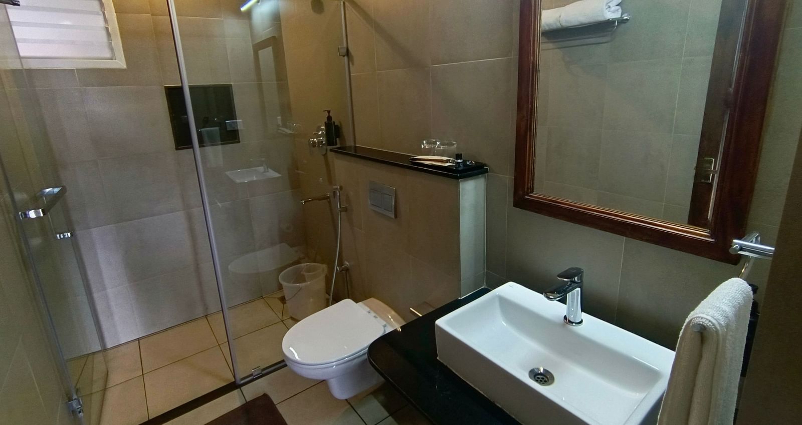 Bathroom with a glass-enclosed shower, sink, and large mirror.