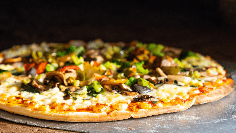 A close up shot of a pizza being removed from an oven at Pizza Bay - Karma Lakelands.