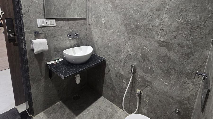 Washroom in Clarks Inn Express, Firozabad, featuring a sink, toilet and a sleek mirror.