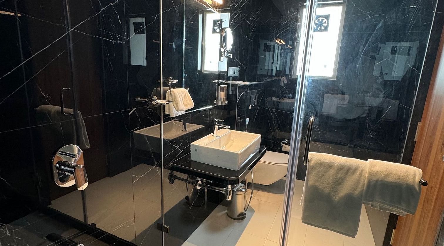 Overview of the bathroom with the shower area in view inside luxury room - Hotel Mumbai House, Valnai, Malad