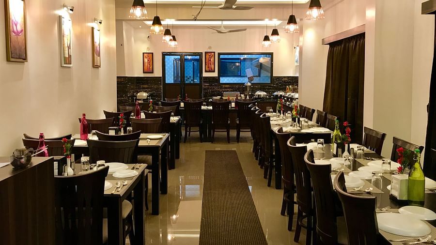 A dining area with plates and glasses placed on the table at Hotel Altitude, Madikeri.