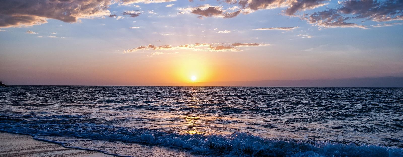 An overview of a beach with the sun setting in the background