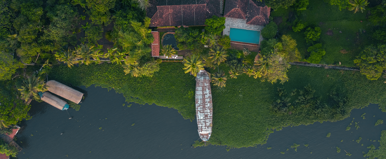 An aerial shot of BluSalzz Villas - Muhamma Resort, Alleppey surrounded by greenery and the Vembanad Lake