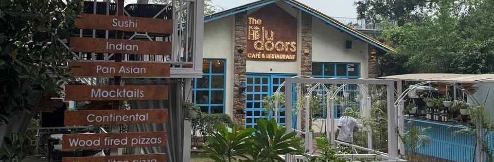 Exterior of 'The Blu Doors Cafe and Restaurant showing a menu sign with various cuisines listed.