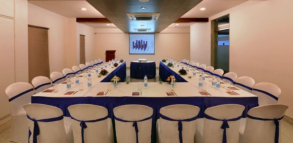 A long conference table with chairs, water bottles, and presentation materials in a meeting room with a projector screen.