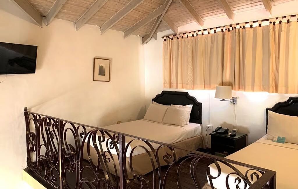 A bedroom with a bed and a decorative railing overlooking another area | Junior Suite | Altamont Court, Jamaica