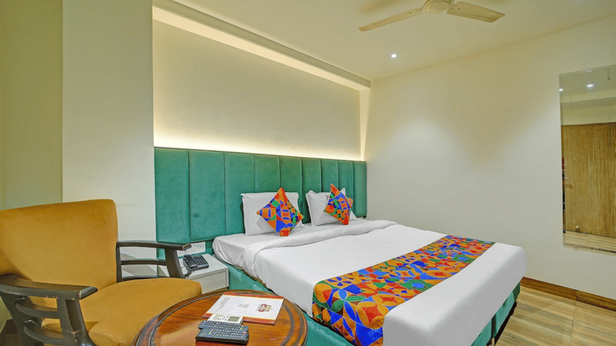 Stylish twin bedroom with vibrant bed runner, cozy seating and modern decor at Hotel Maurya, Bhopal.
