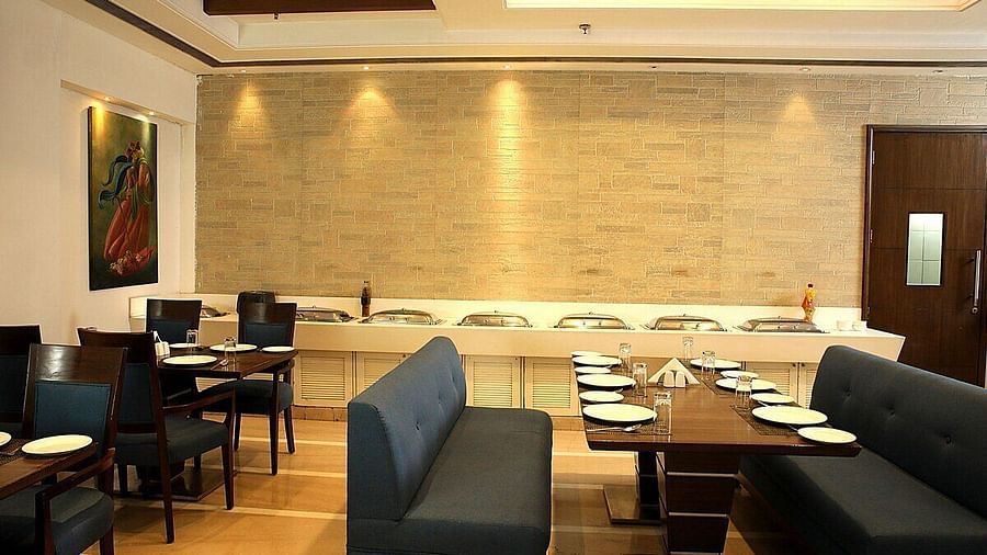 Tables and chairs neatly arranged with cutlery set on the table at Café Inde, Inde Signature Tower, Gurgaon