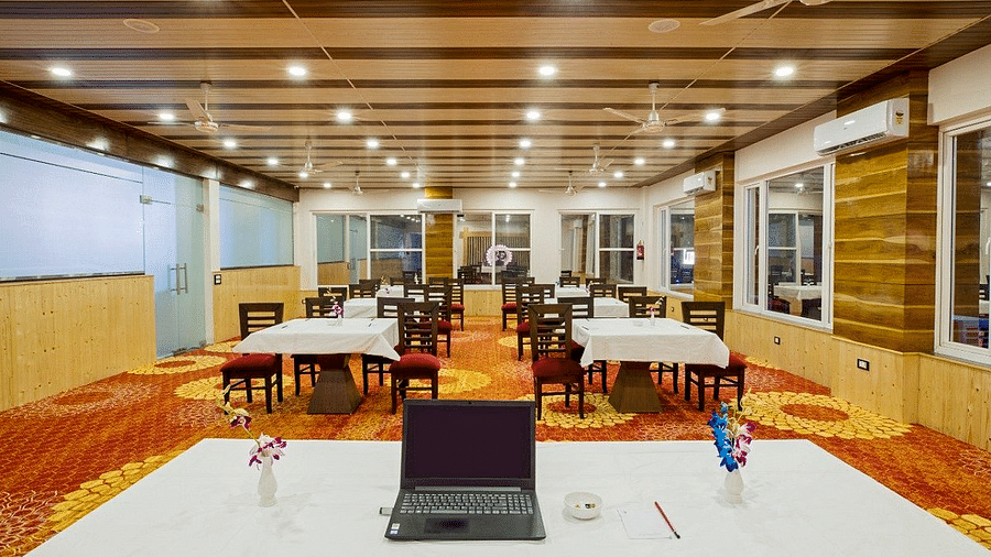 Front view shot of the Banquet Hall at Regenta Inn DLS overlooking the tables and chairs in the front of the main table.