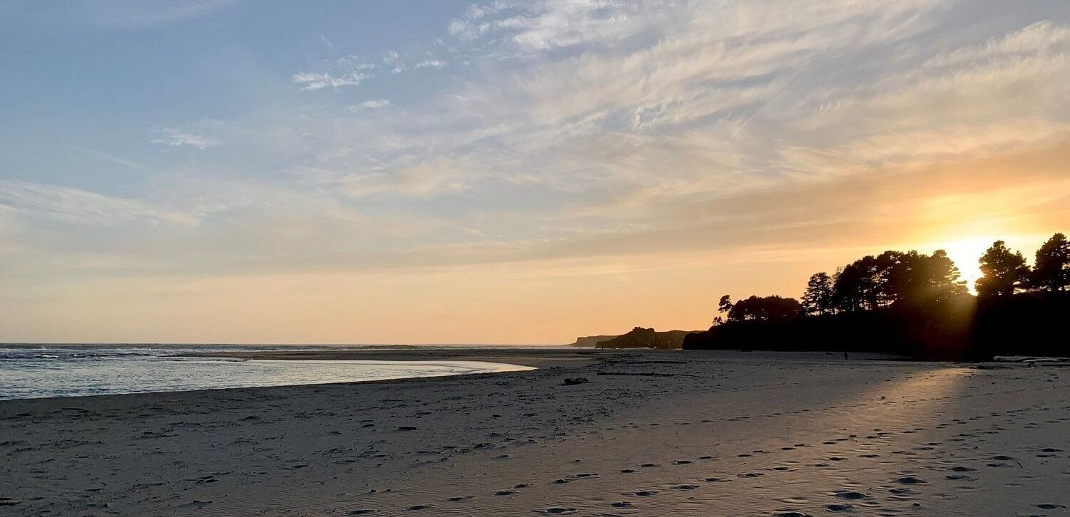 A stunning sunset over a water body, with sandy beach access.