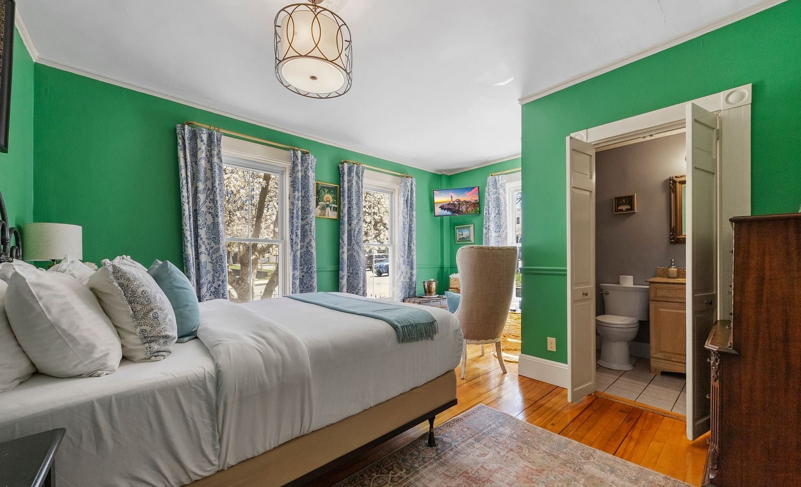 A bedroom with , green walls, and large windows lat Hartstone Inn.