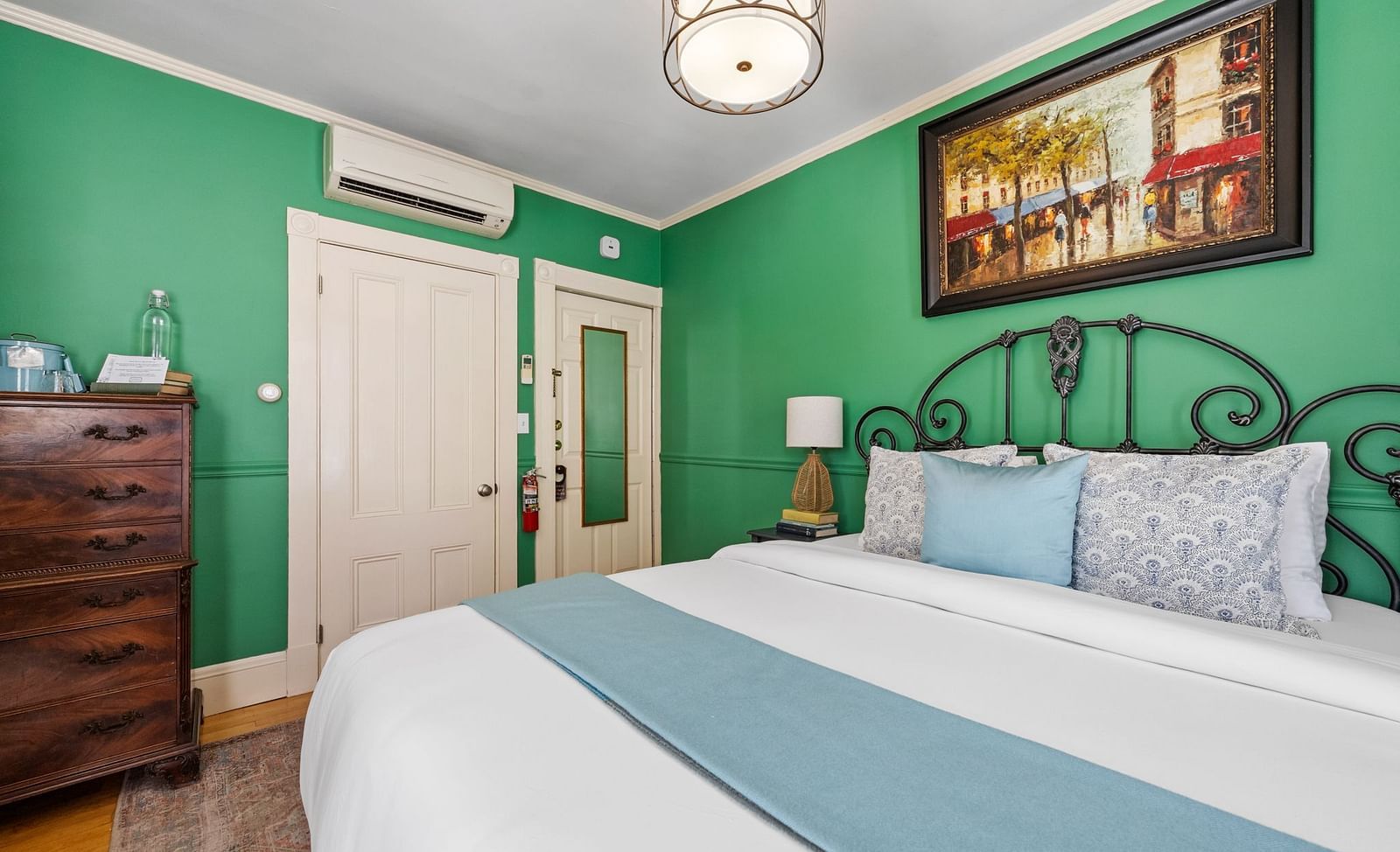 A bedroom with green walls, white bedding, and a decorative iron bed frame at Hartstone Inn