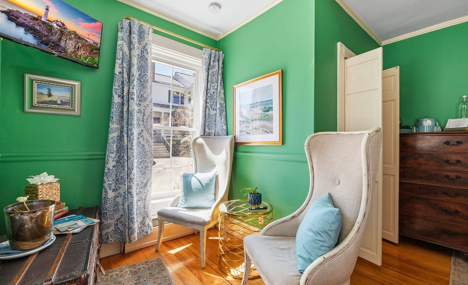 Bright sitting room with green walls, high-back chairs, and large windows at Hartstone Inn.