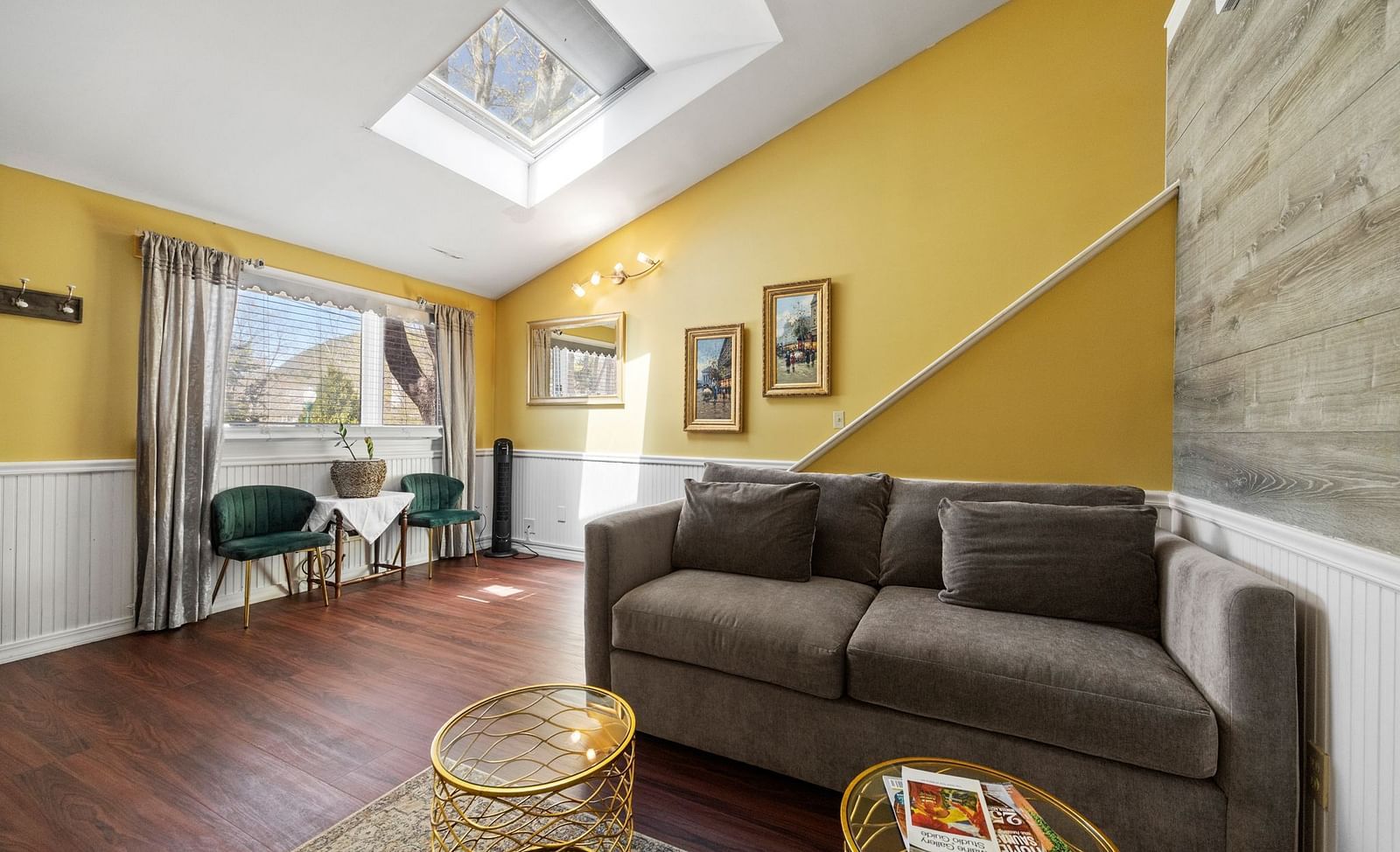 Modern living room at Hartstone Inn with a skylight, yellow walls, a gray couch, and a round wicker coffee table