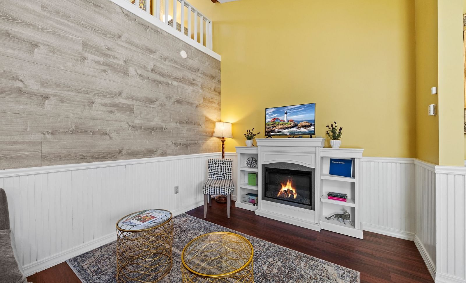 Cosy indoor lounge at Hartstone Inn with yellow walls, a fireplace, a gray armchair, and a staircase