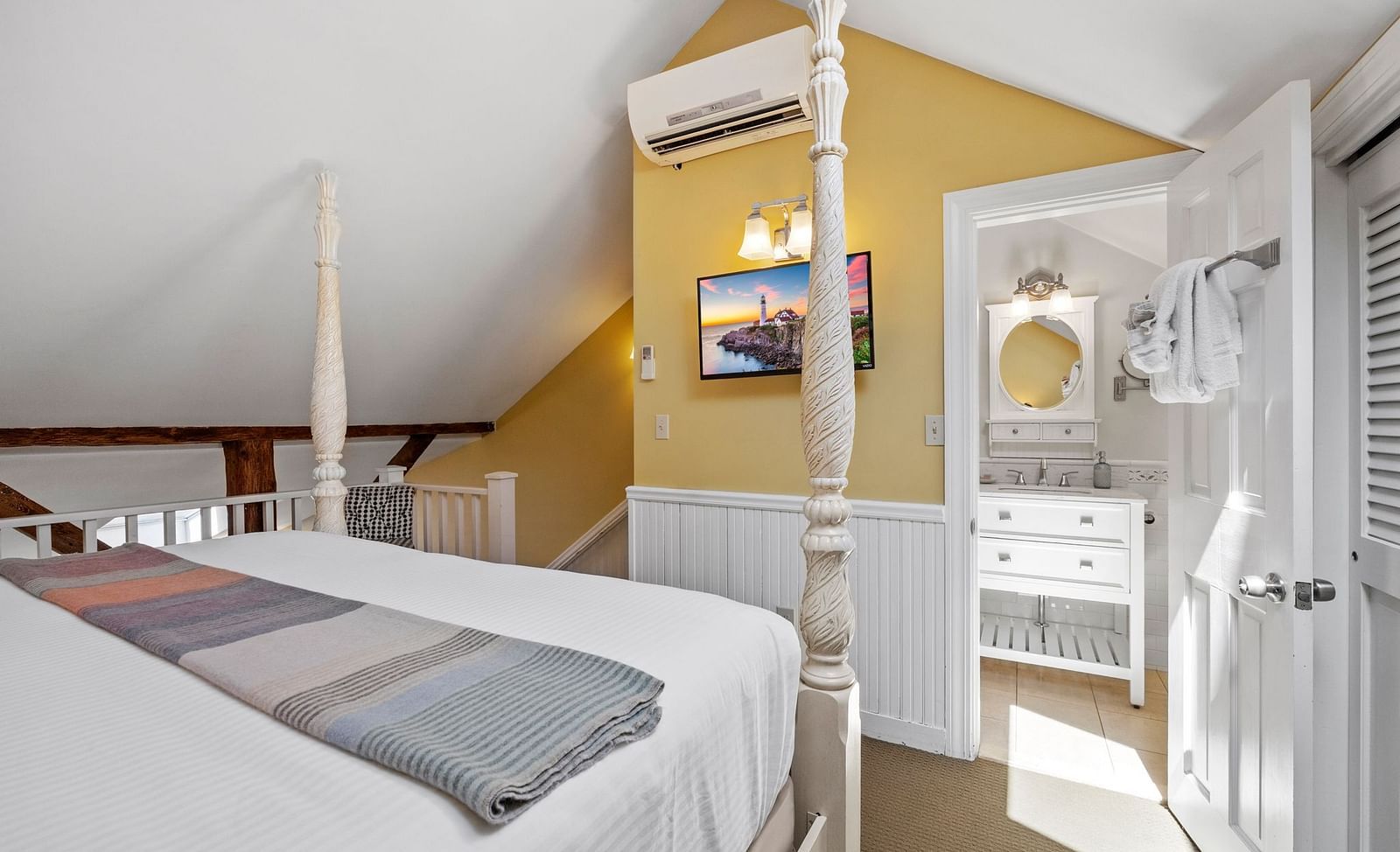 A room with double bed, Ac, tv and warm yellow accent walls at Hartstone Inn