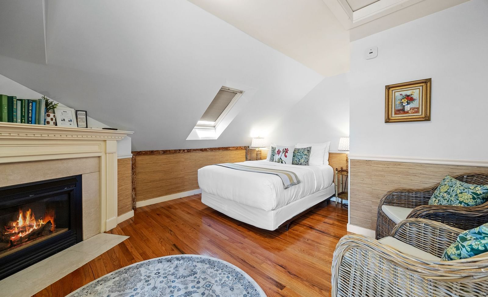 A room with fireplace, cushioned chairs, and slanted ceiling at Hartstone Inn.