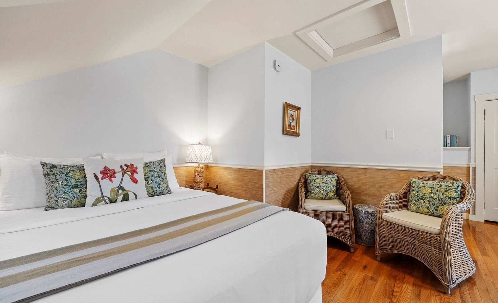 A room with bed, white walls, and floral themed pillows at Hartstone Inn.