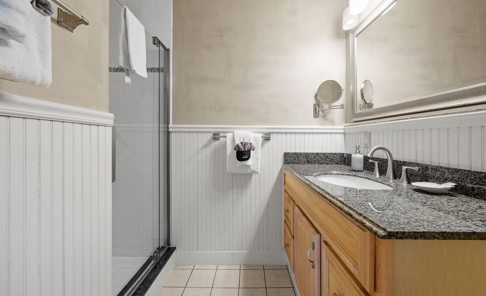 A bathroom with shower area, a small mirror, towels and a sink at Hartstone Inn.