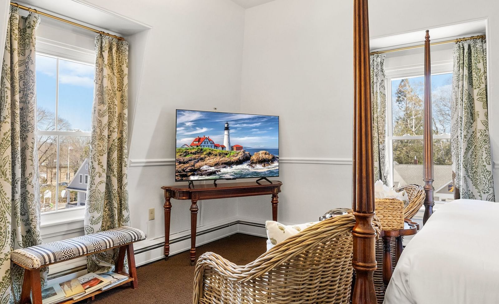 Room featuring bed, wall-mounted TV, chair, books placed near the big glass window at Hartstone Inn