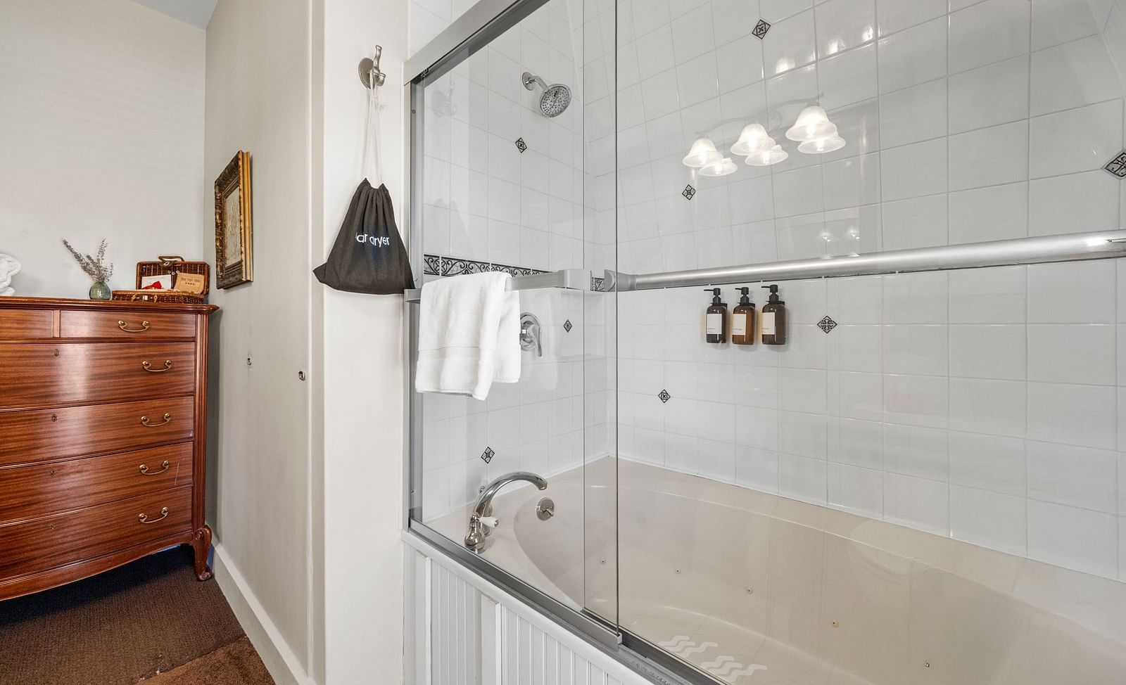 White bathroom with bath tub combo and mounted toiletry dispensers at Hartstone Inn.