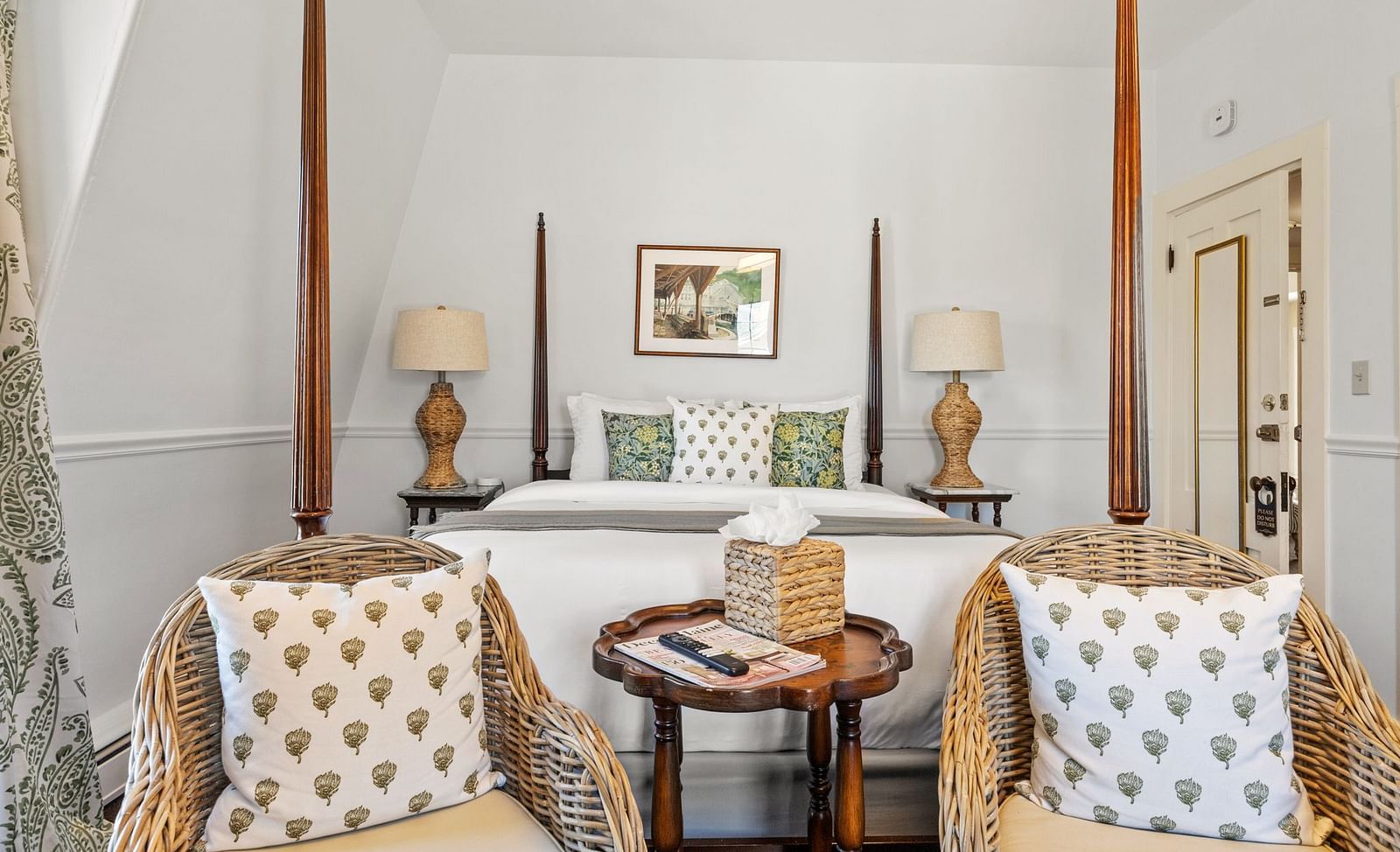 A bedroom with a four-poster bed and cosy sitting area with two armchairs at Hartstone Inn.