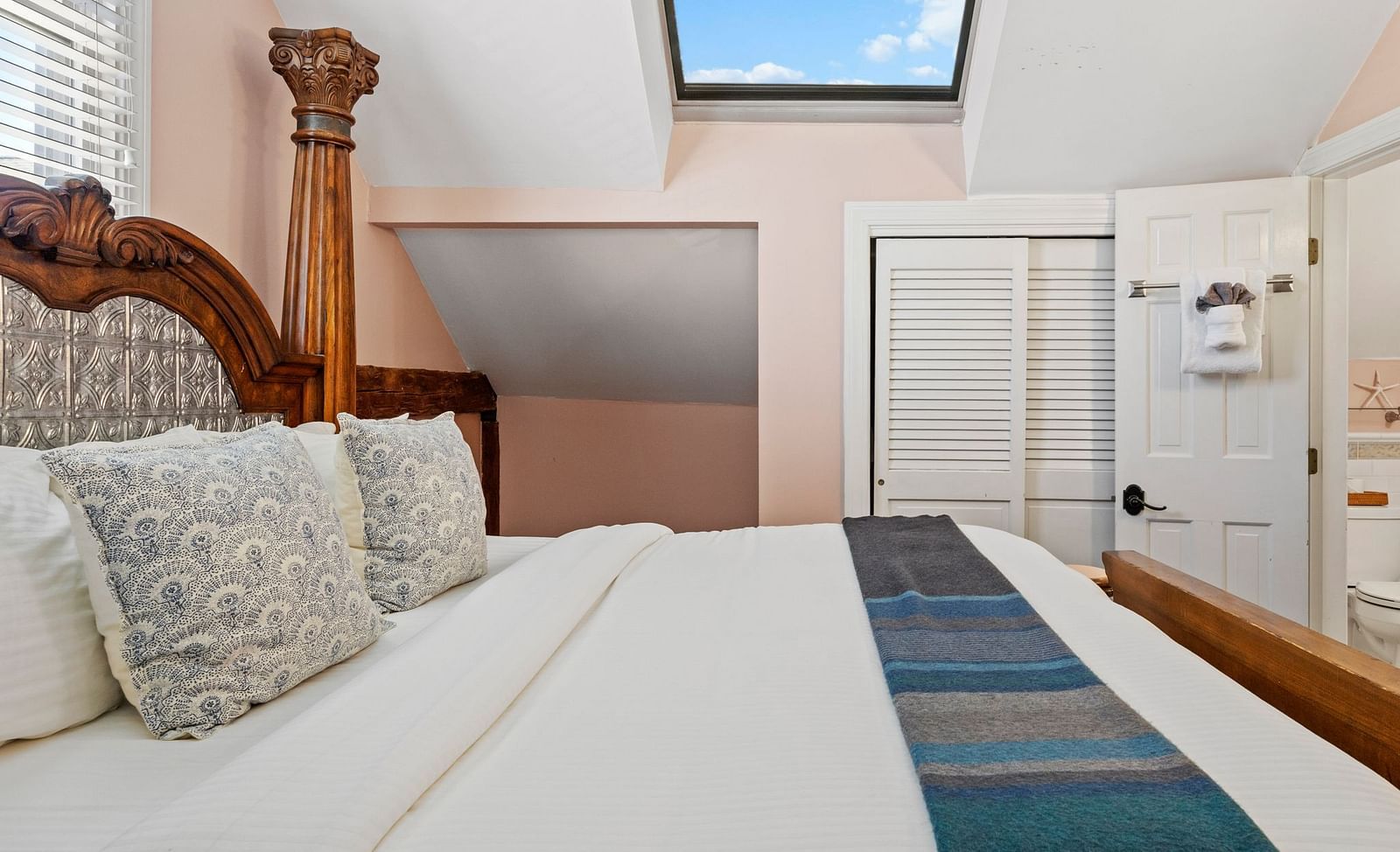 A bedroom with skylight, wicker headboard, and pastel walls at Hartstone Inn