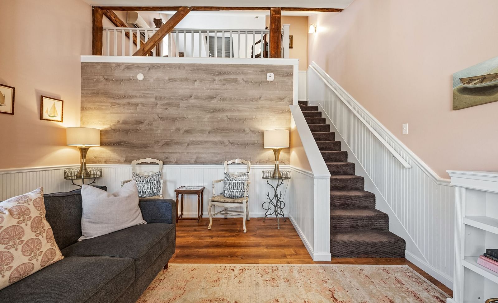 A room with sofa, wood accent wall, and stairway leading to loft at Hartstone Inn