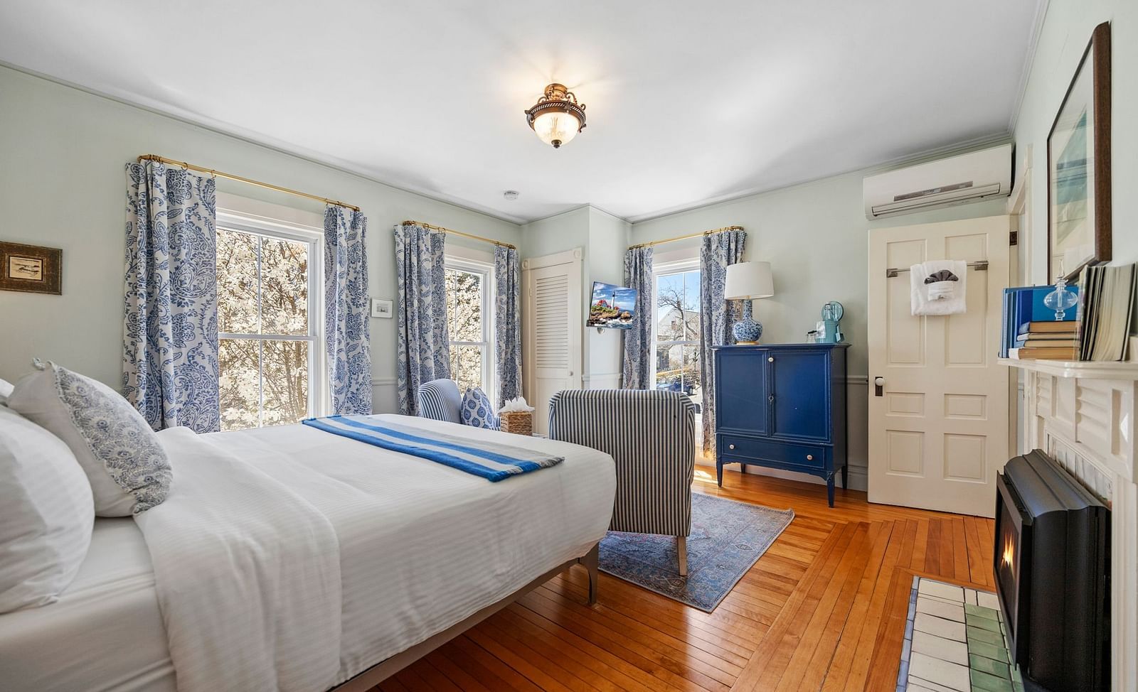 A air conditioned room with queen size bed and floral curtains at Hartstone Inn