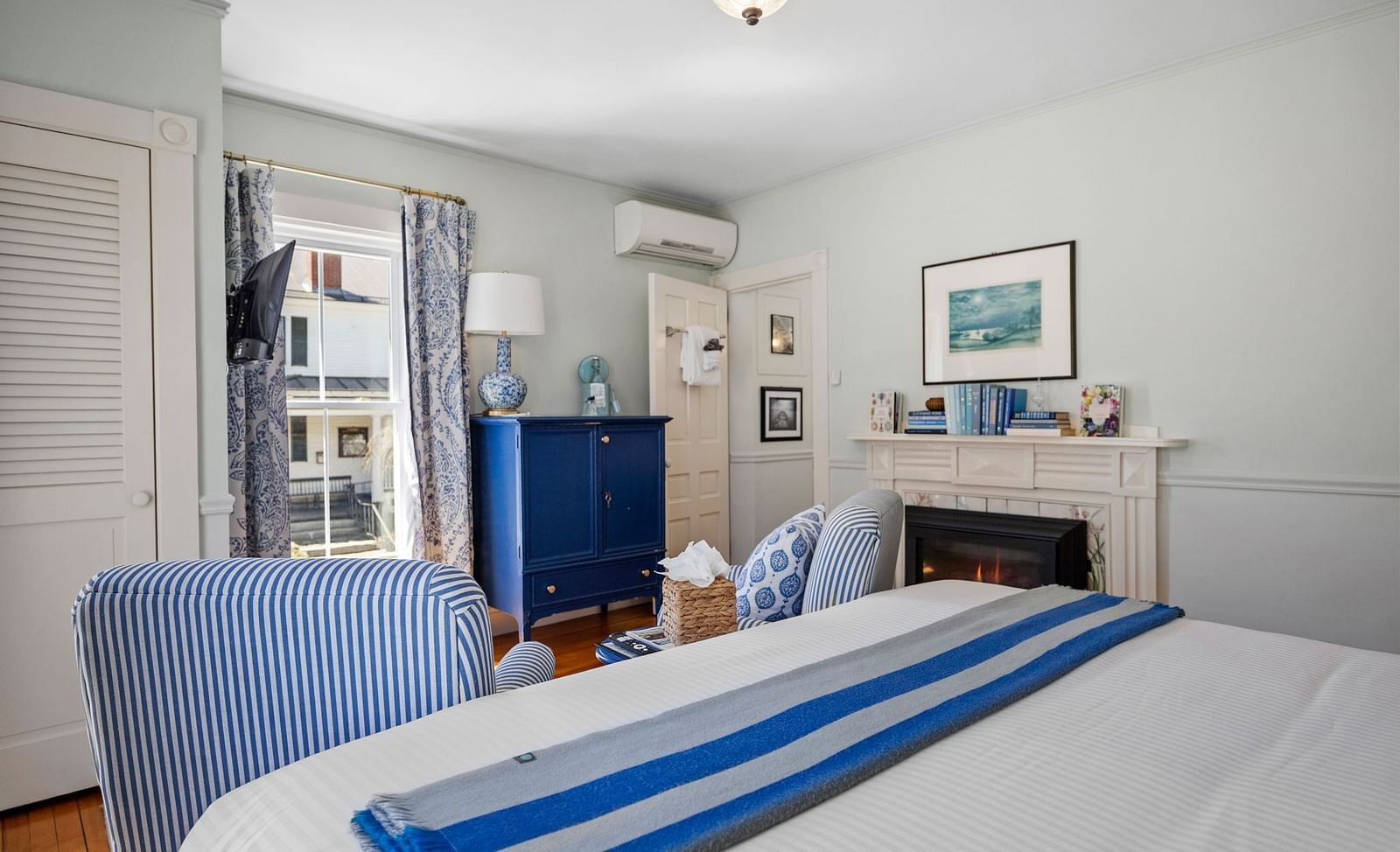 Guest room with a table, armchairs, and bed with blue-striped runner at Hartstone Inn