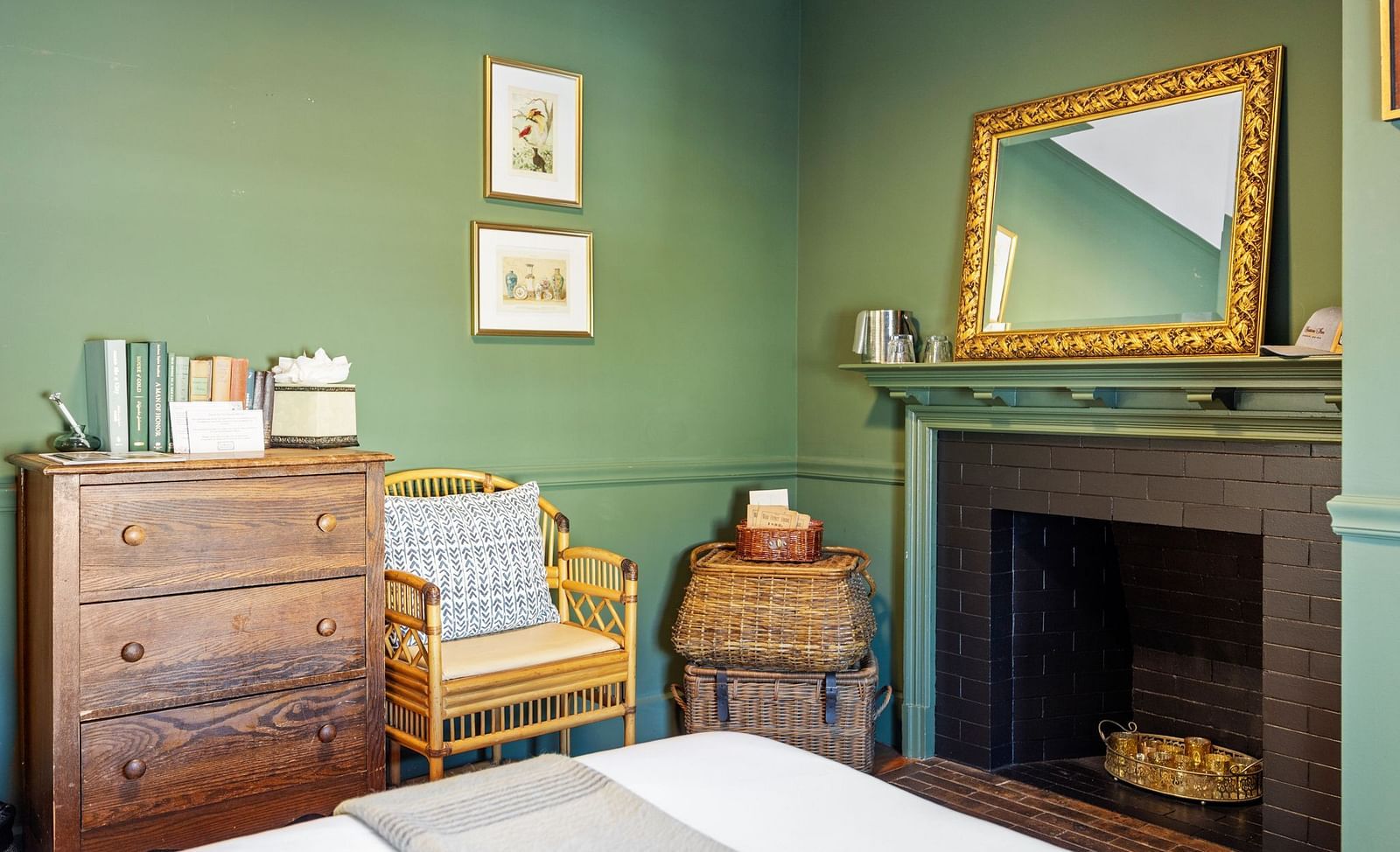 Green-toned bedroom with vintage mirror, fireplace, and wooden table at Hartstone Inn