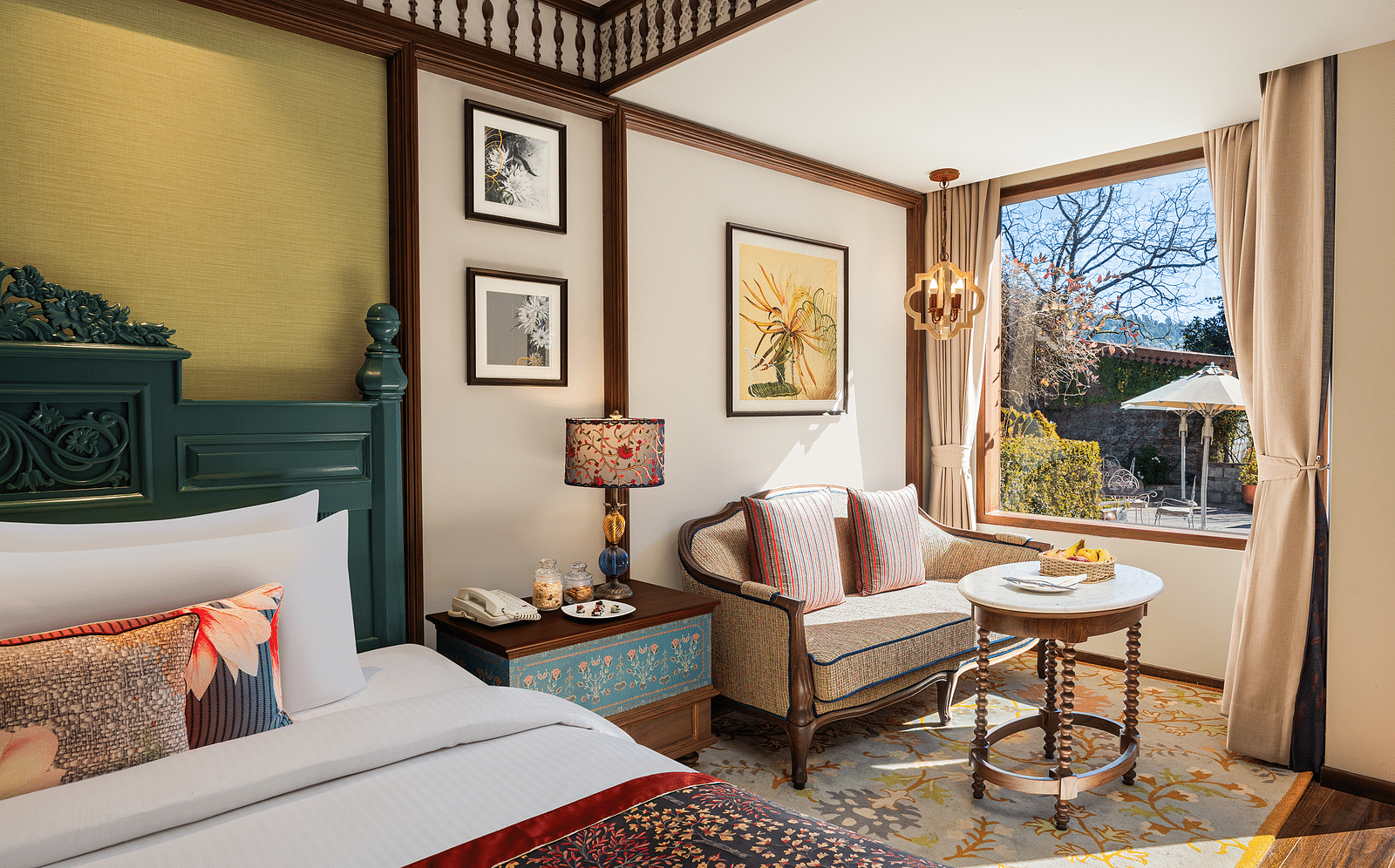 Premium Garden Room at naini retreat, nainital, A cozy and inviting hotel room with a king-size bed, ornate headboard, bedding. The room features a small sitting area with a sofa and a side table, as well as a large window overlooking a garden.