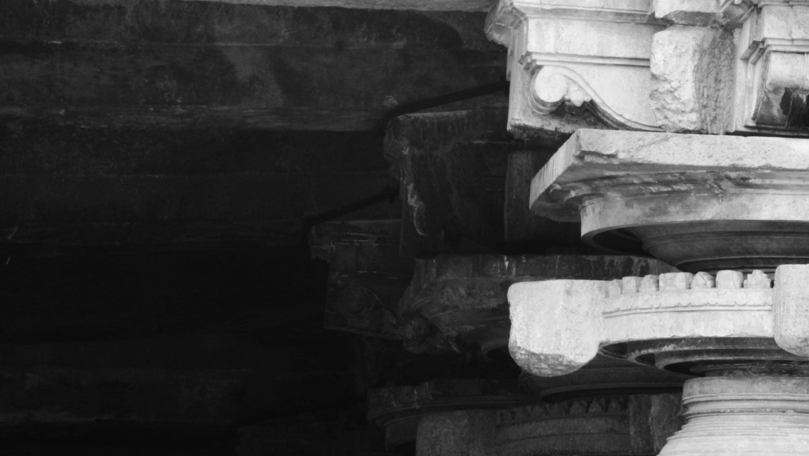 A pillar of a temple with intricate details and another pillar in the shadow behind it