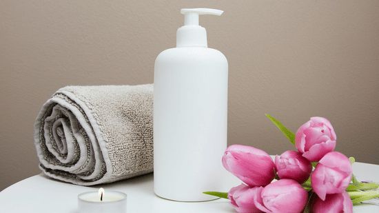 A bunch of tulip flowers kept next to a bottle and a rolled towel by a tealight candle