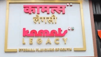 Close-up of Kamats Legacy Mira Road signage highlighting the brand name and its promise of authentic South Indian flavours.