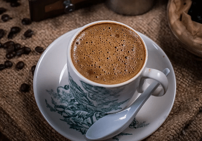 A cup with a drink, a spoon kept beside the cup. 