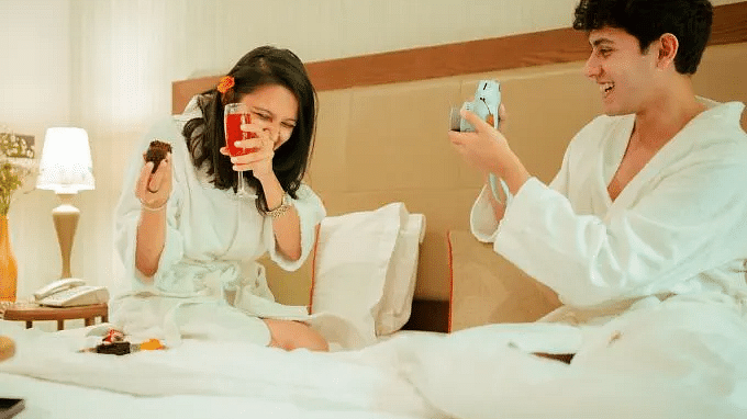 Two people in bathrobes holding drinks and talking in a hotel room at Karma Chalets.
