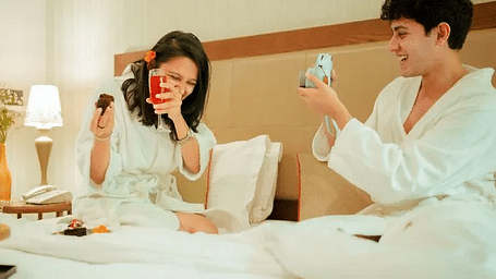 Two people in bathrobes holding drinks and talking in a hotel room at Karma Chalets.