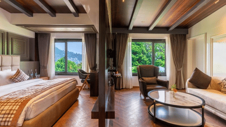 A panoramic view of a bedroom and living space separated by a dark wood partition under a beamed ceiling | Lawrence Solitaire Resort, Nainital