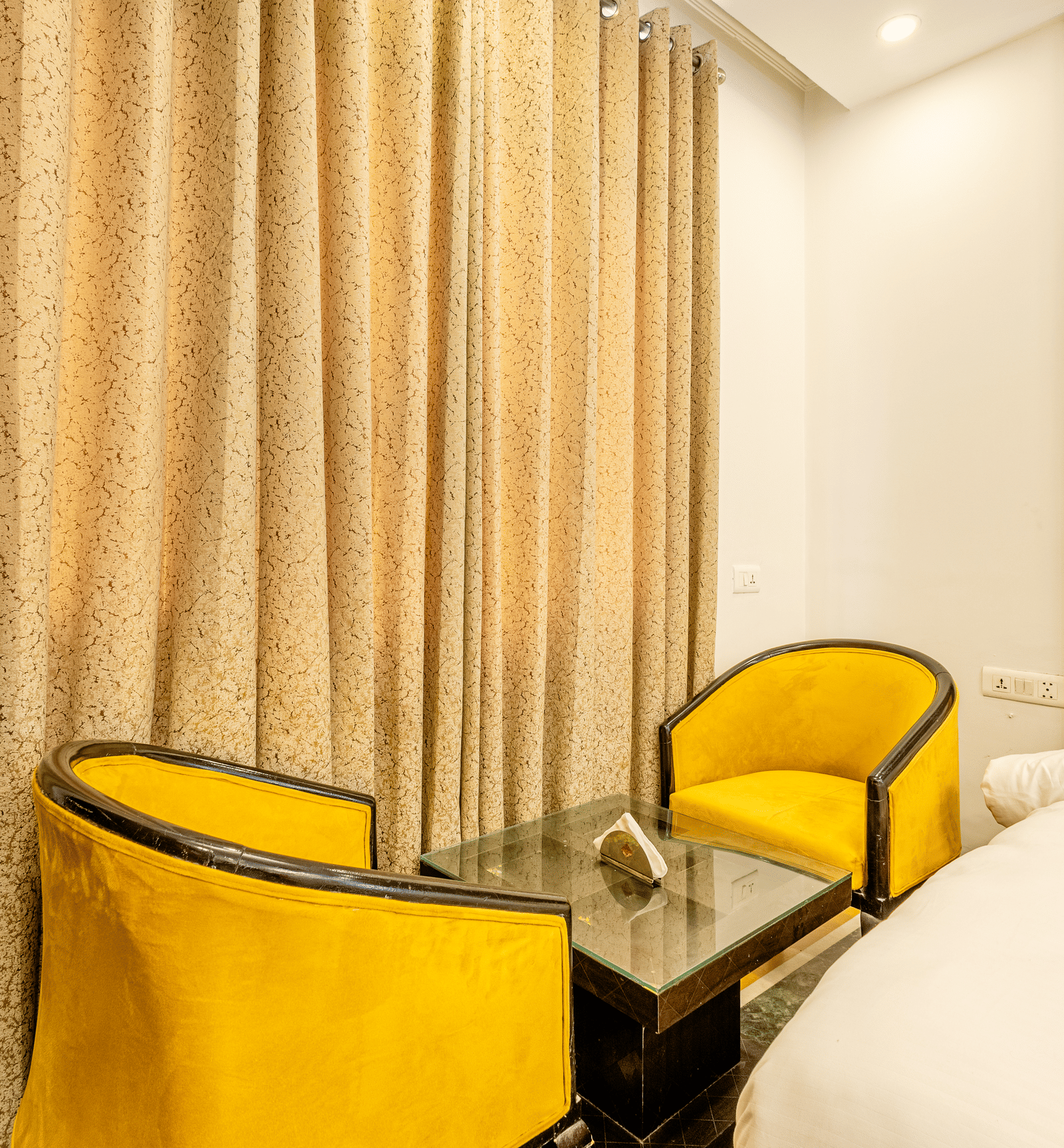 two yellow chairs facing each other with a small tea table between them in the superior king room at Lime Tree Hotels and Banquet Hall Near Huda Metro, Gurgaon
