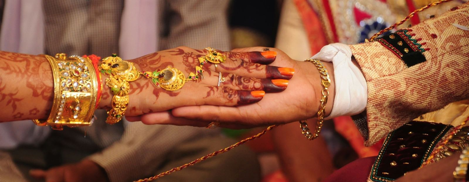 This image captures a close-up of a traditional Indian wedding ceremony. The bride and groom's hands are clasped together