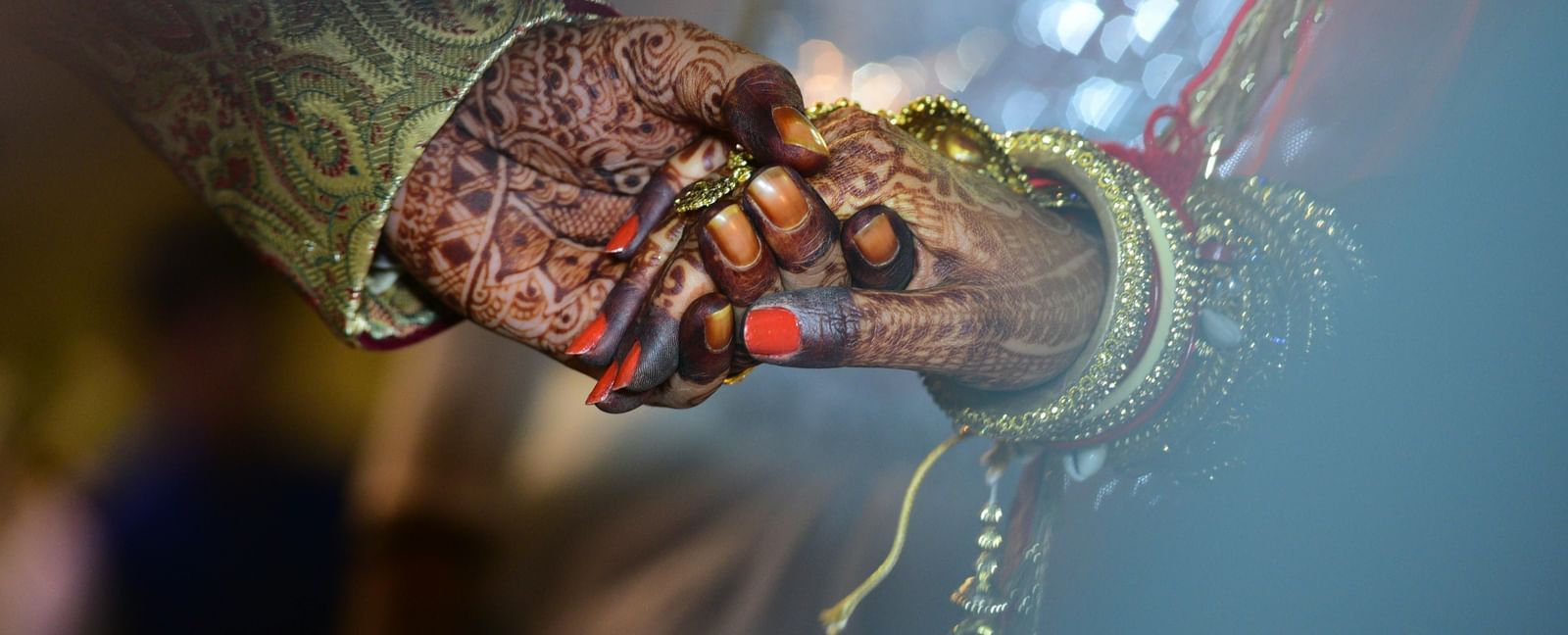 A close up view of the bride and groom holding hands.
