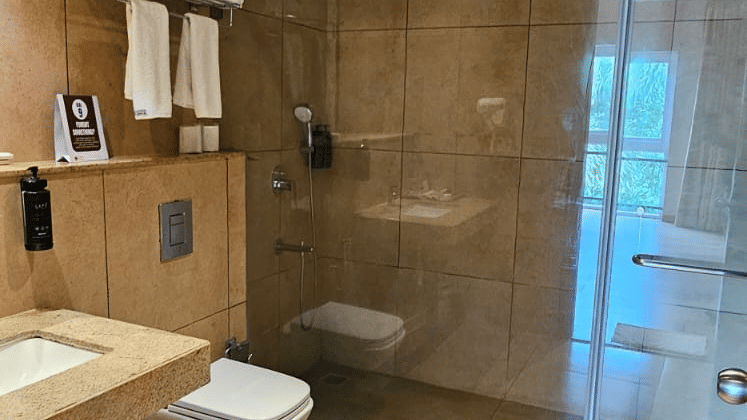 Tiled bathroom featuring a glass shower cubicle and vanity unit at Cholaa Dynasty, Kumbakonam.