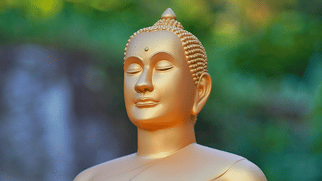 A close up of a Buddha statue in golden hue in a meditative posture