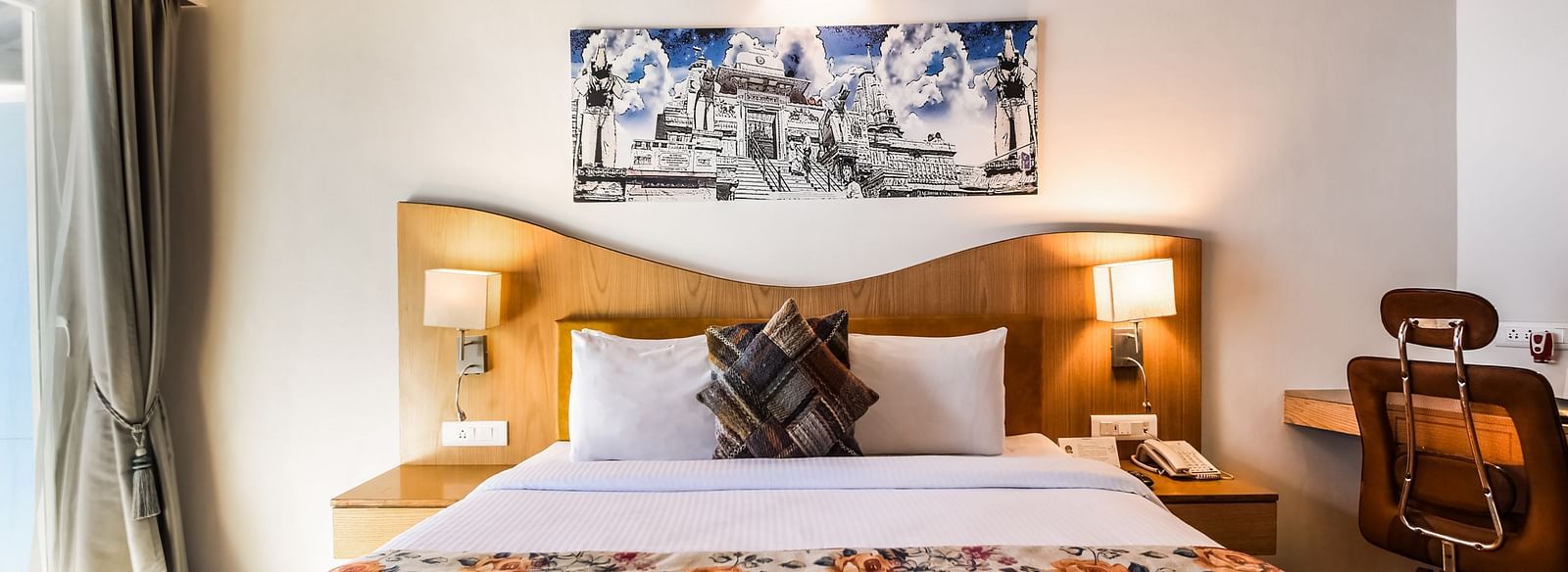 A bright room with a bed featuring a floral patterned runner, a desk, and a unique ceiling design. - Bamboo Saa Resort & Spa, Udaipur