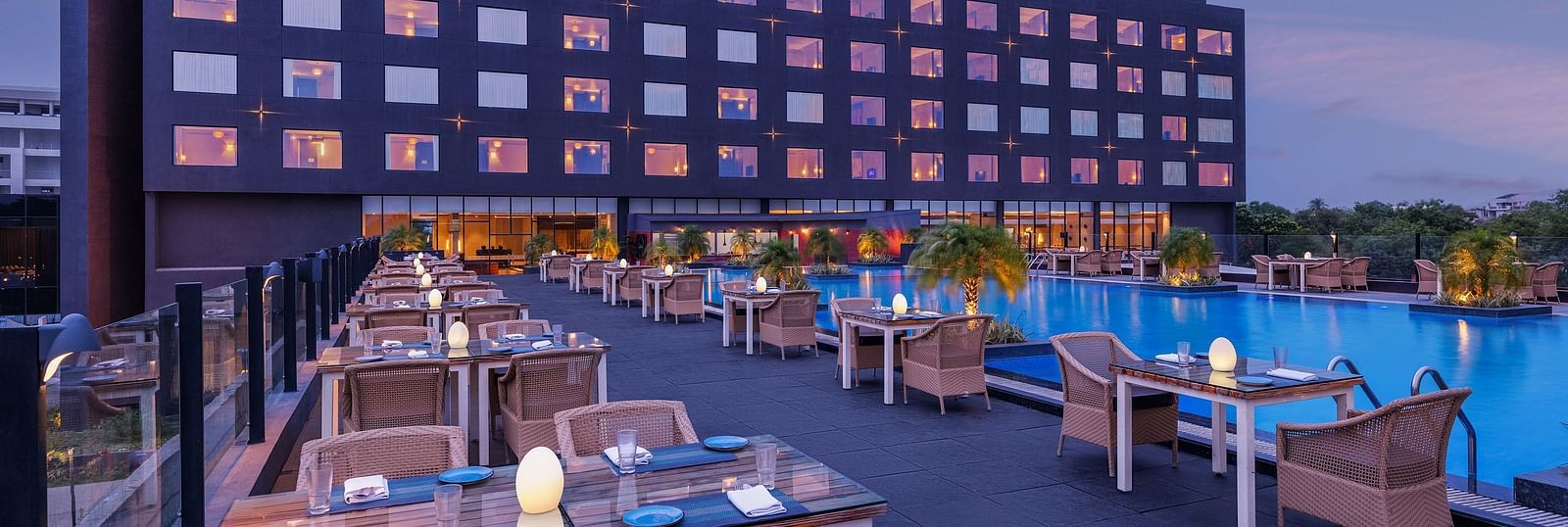 Poolside seating arrangement with the Essentia Luxury Hotel, Indore building in the backdrop