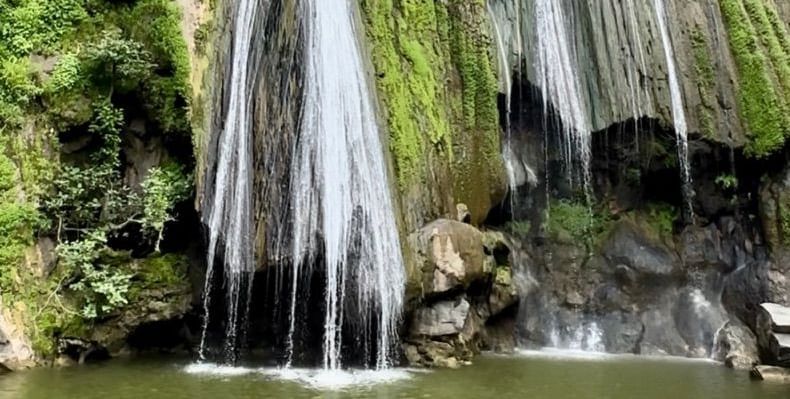 Bheel Beri Waterfalls showcasing water running down through rocky mountain surrounded by plants. 