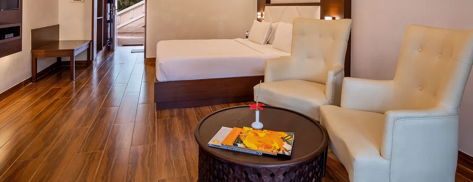 A Deluxe room with two arm chairs with round table with art photo frame in the wall at Avana Resort