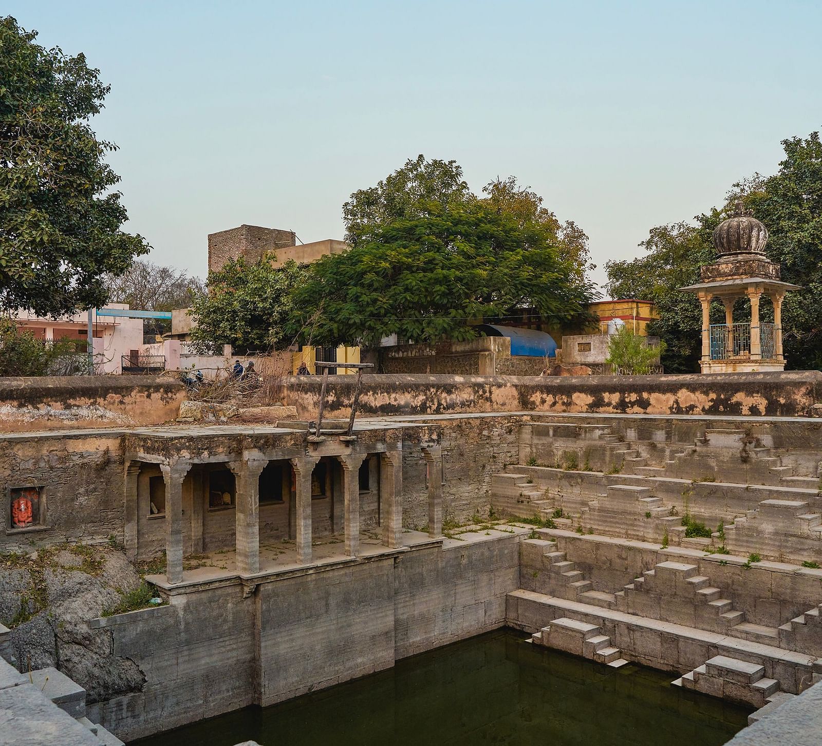 image of a step well surrounded by trees constructed in a typical rajasthani architecture